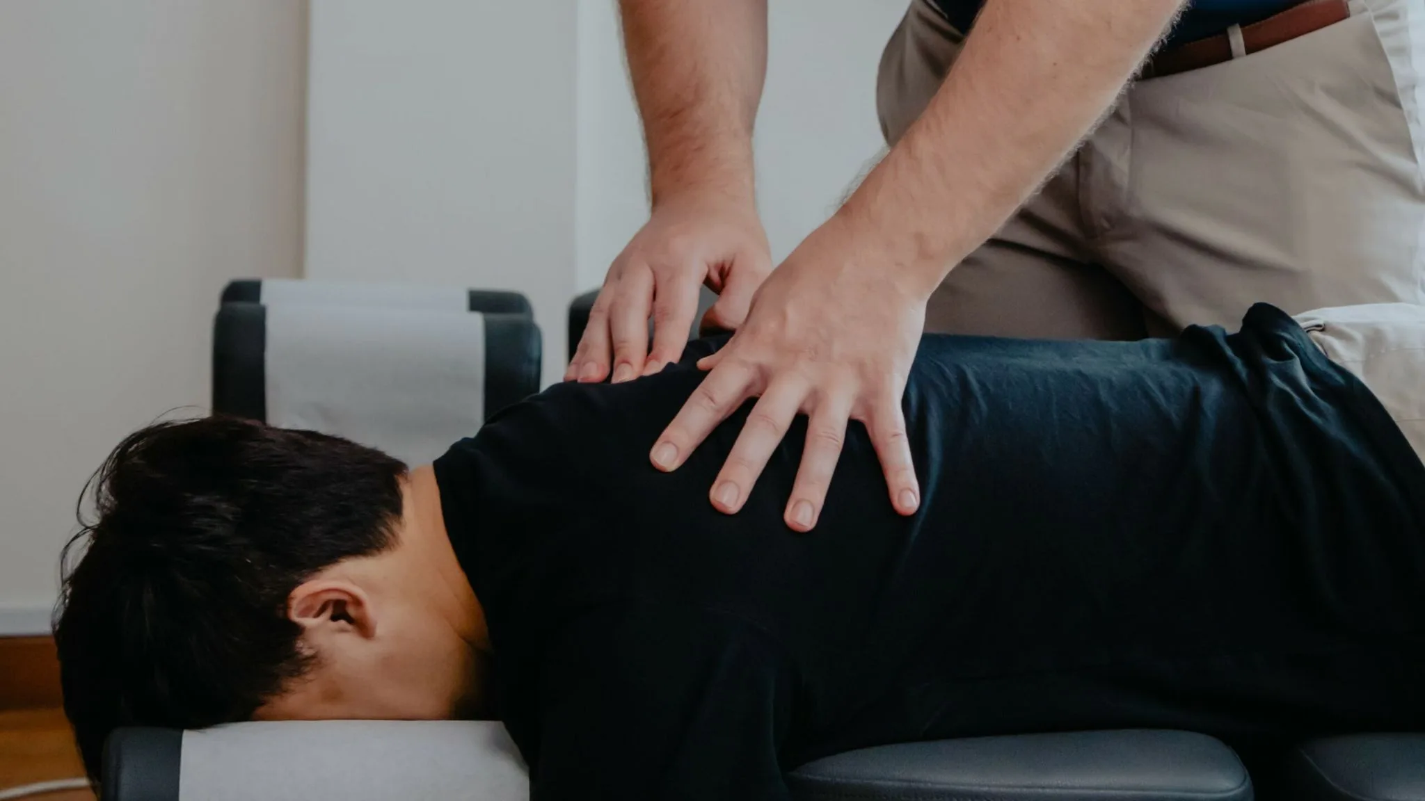 A man receiving a chiropractic treatment while seated in a Newmarket wellness clinic, appearing relaxed and content.