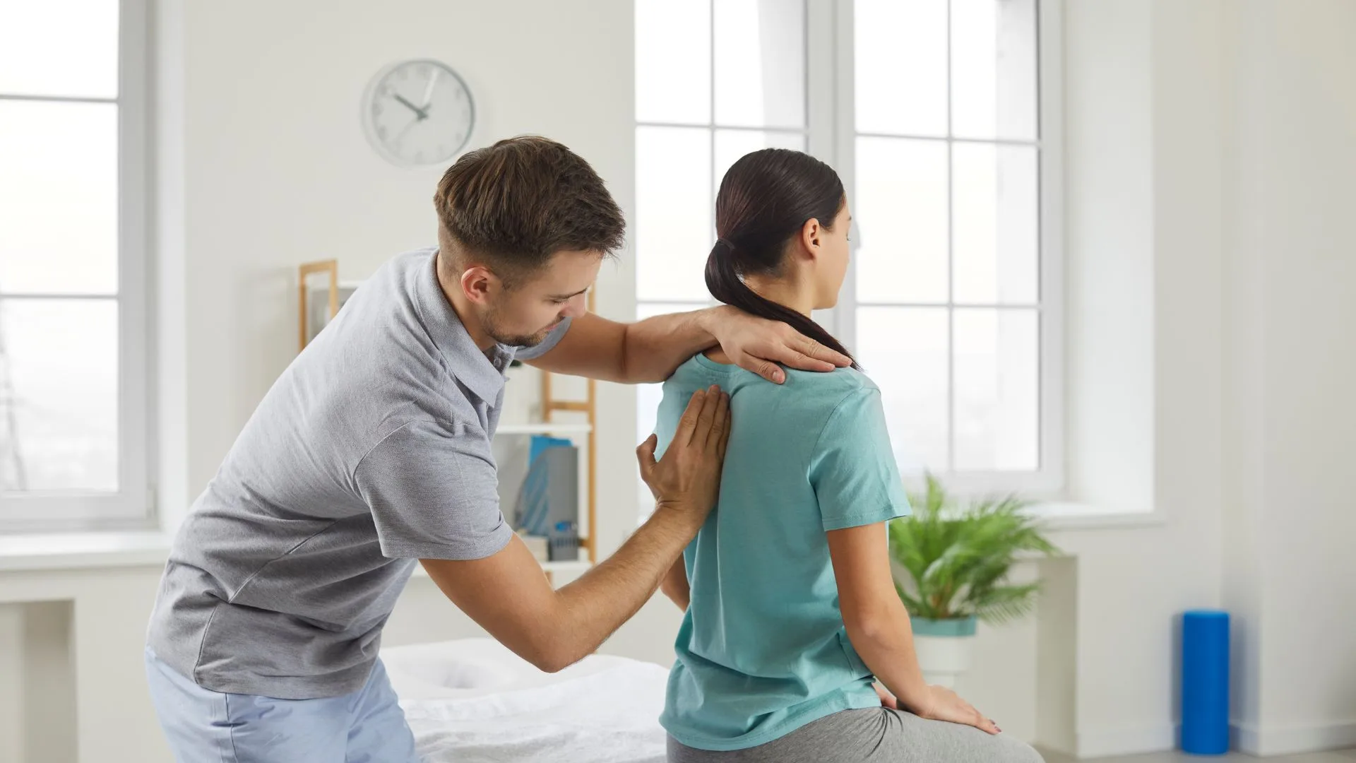 A chiropractic professional conducts a physical examination on a female patient in a clinical setting.