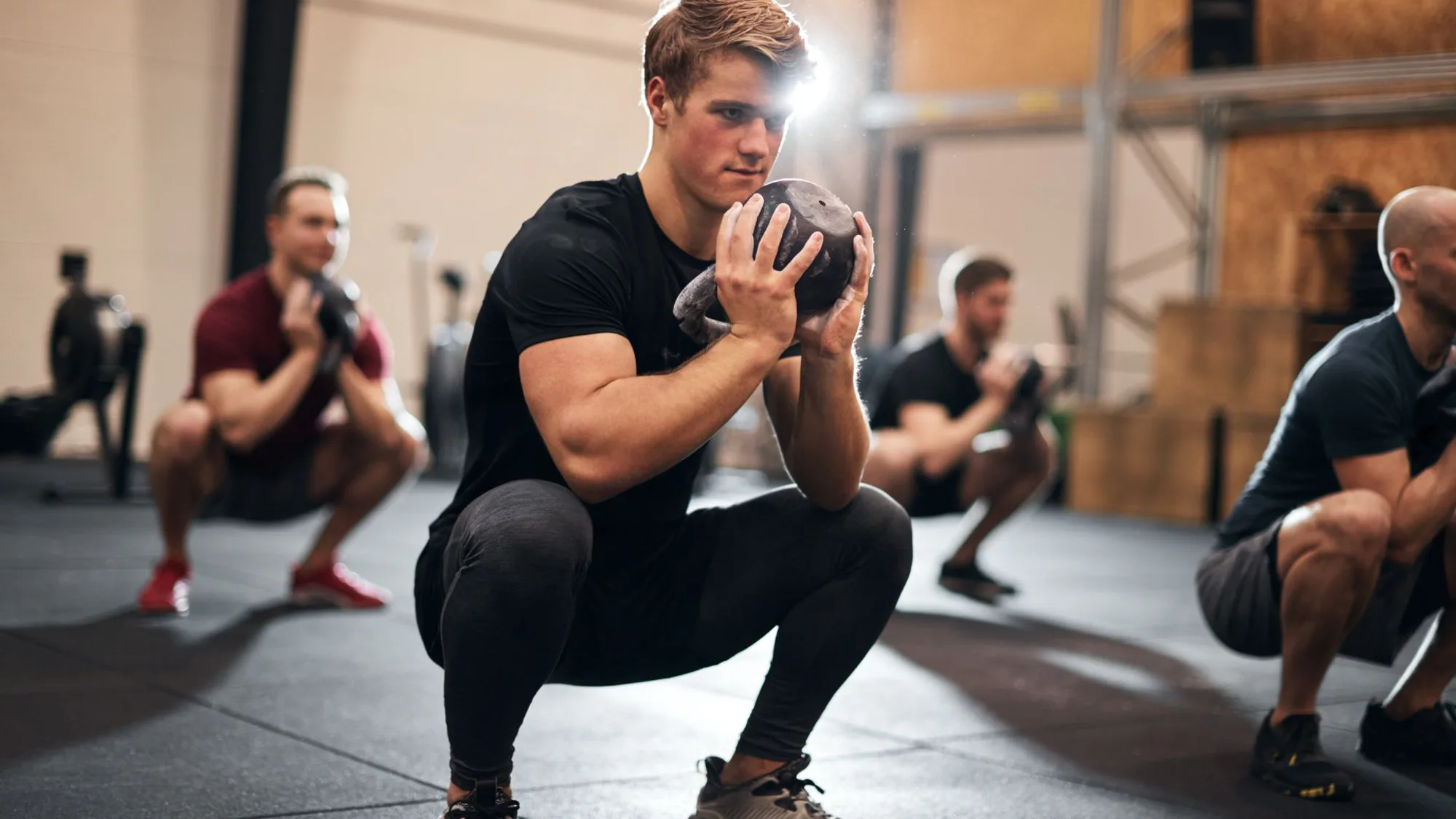 A group of men performing kegel squats together in a gym, as part of Pelvic Floor Physiotherapy for men