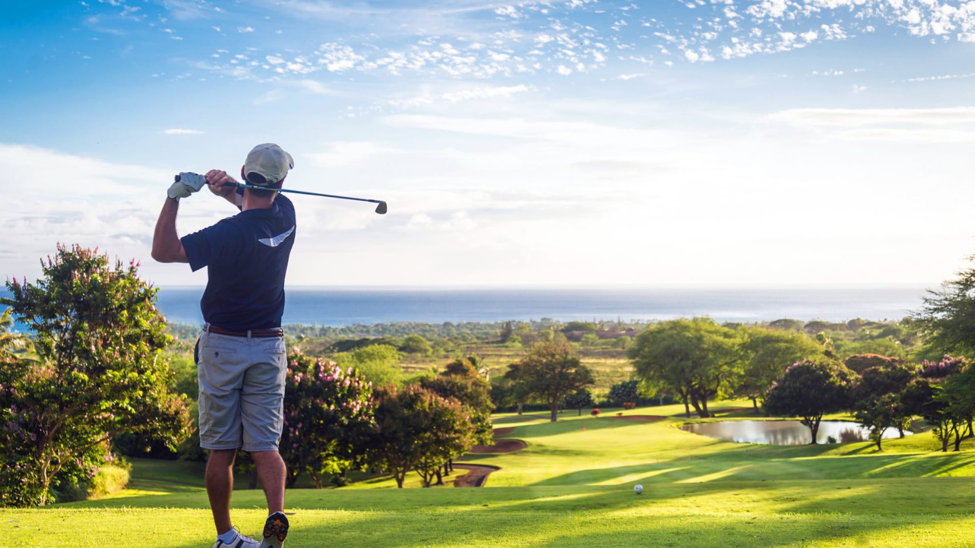 A man swings a golf club on a lush green field, focusing intently on his shot.